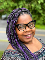 Picture of Black woman with black glasses and braids smiling