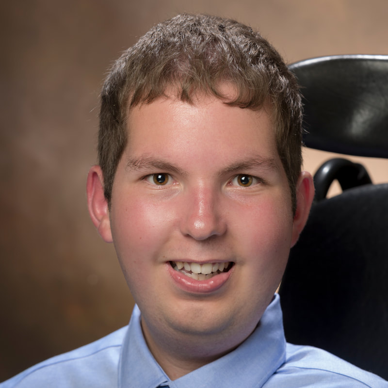 Headshot of Dan Darkow, a young white man with short brown hair and a button-up shirt sitting in his power chair.